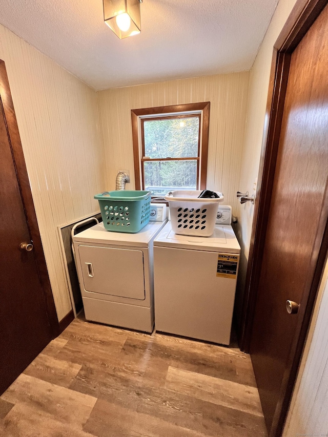 laundry room with separate washer and dryer, a textured ceiling, and light wood-type flooring