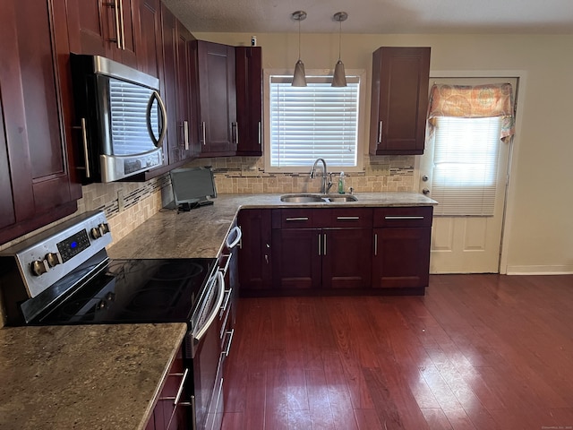 kitchen featuring pendant lighting, appliances with stainless steel finishes, decorative backsplash, sink, and light stone counters