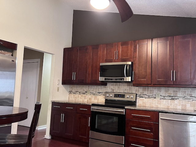 kitchen with light stone countertops, backsplash, appliances with stainless steel finishes, and lofted ceiling