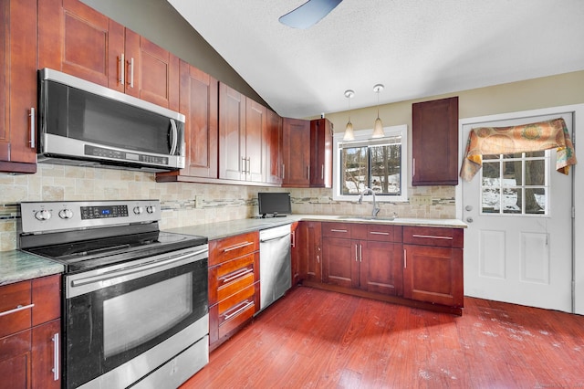 kitchen with sink, hanging light fixtures, appliances with stainless steel finishes, dark hardwood / wood-style floors, and backsplash