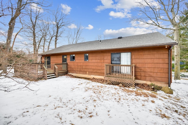 snow covered back of property with a deck