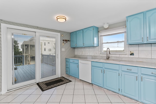 kitchen with light tile patterned flooring, blue cabinets, sink, dishwasher, and backsplash