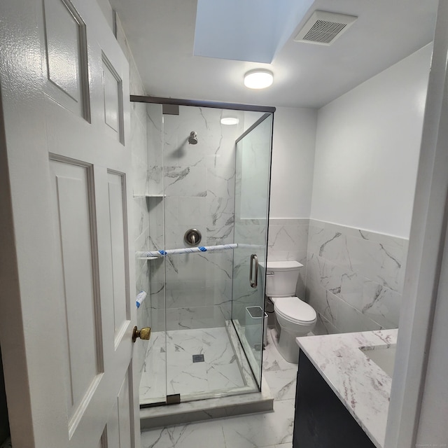 bathroom featuring tile walls, vanity, toilet, and an enclosed shower