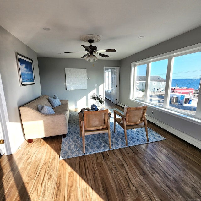 living room featuring hardwood / wood-style flooring, a baseboard radiator, a water view, and ceiling fan