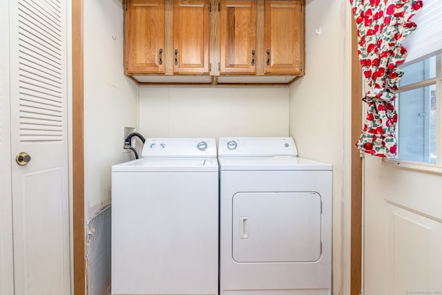 clothes washing area featuring cabinets and washer and dryer