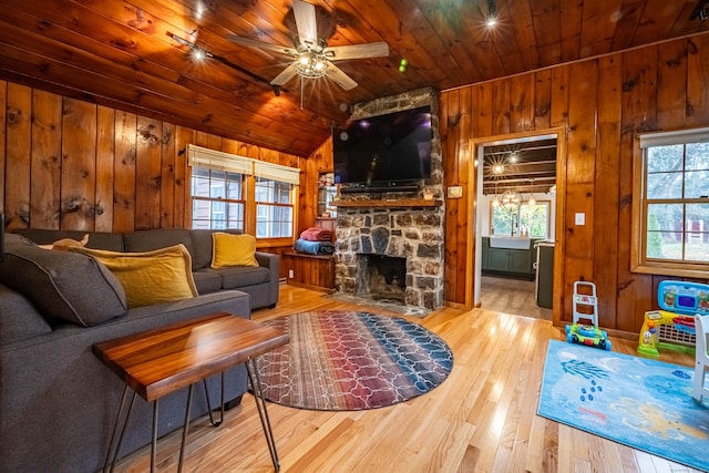 living room featuring light hardwood / wood-style flooring, a fireplace, wooden walls, and wooden ceiling