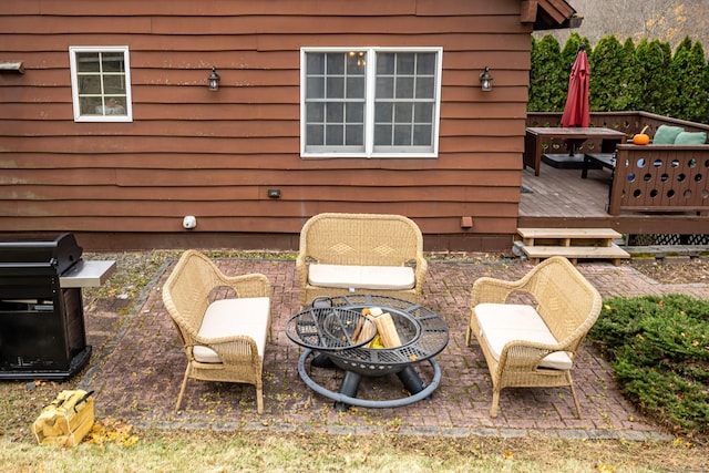 view of patio / terrace featuring a wooden deck, a fire pit, and a grill