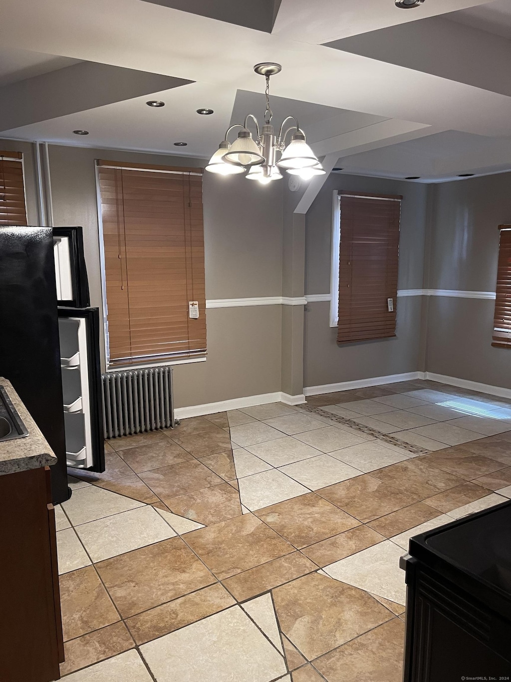 unfurnished dining area featuring a chandelier, light tile patterned floors, and radiator