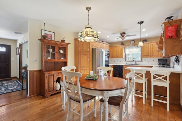 dining space with ceiling fan, sink, and light hardwood / wood-style flooring