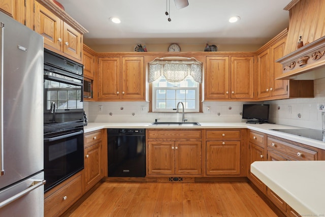 kitchen with sink, backsplash, black appliances, and light hardwood / wood-style floors