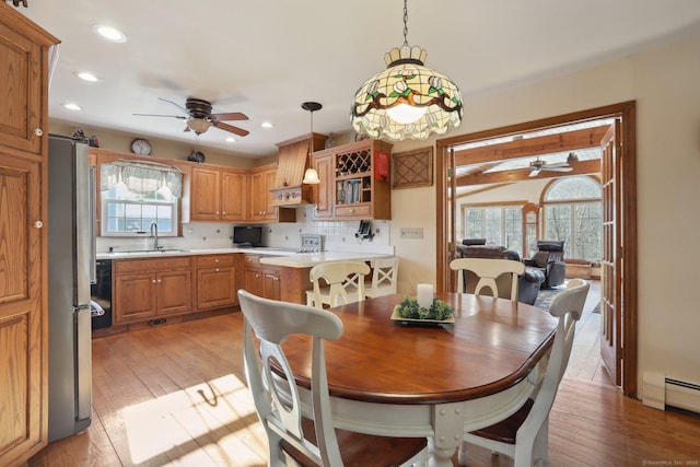 dining area with plenty of natural light, sink, baseboard heating, and light hardwood / wood-style flooring