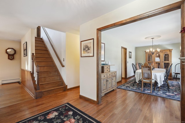 dining space with an inviting chandelier, a baseboard heating unit, and light wood-type flooring