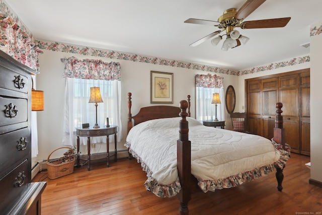 bedroom featuring multiple windows, wood-type flooring, ceiling fan, and a closet