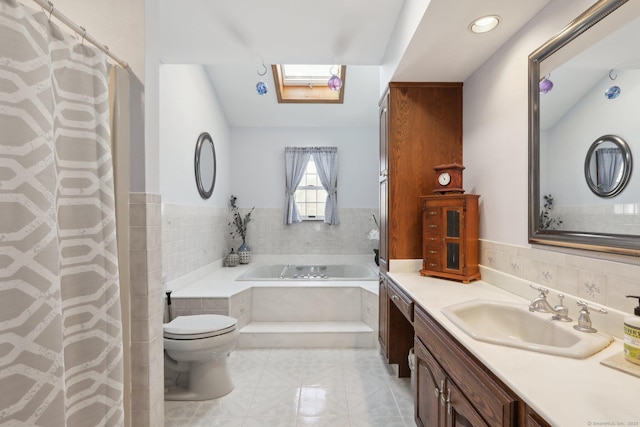 bathroom featuring vanity, a bath, a skylight, and toilet