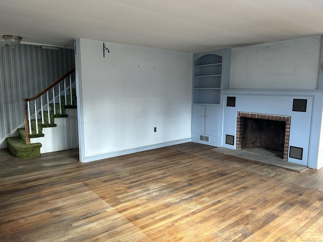 unfurnished living room featuring hardwood / wood-style flooring, a fireplace, and built in features