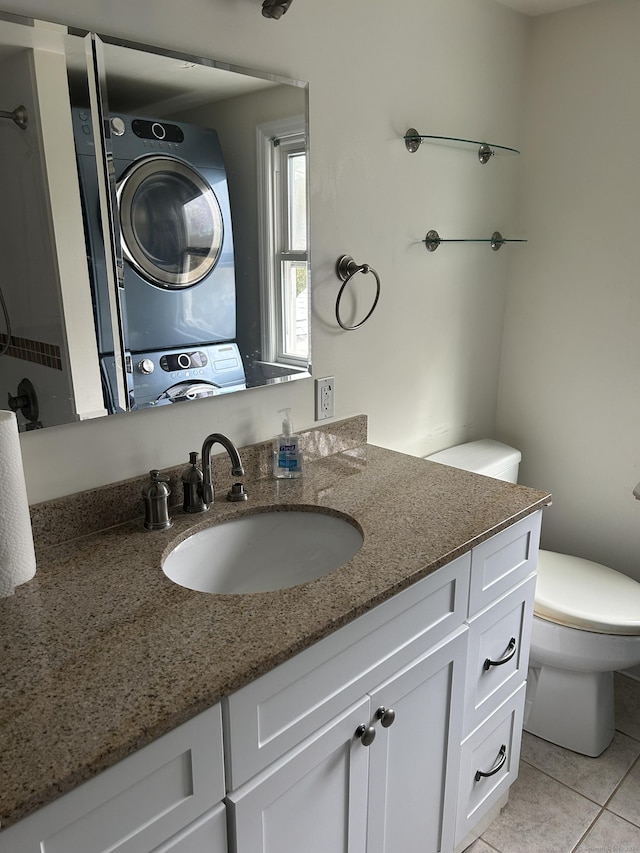 bathroom with stacked washer and dryer, vanity, tile patterned floors, and toilet