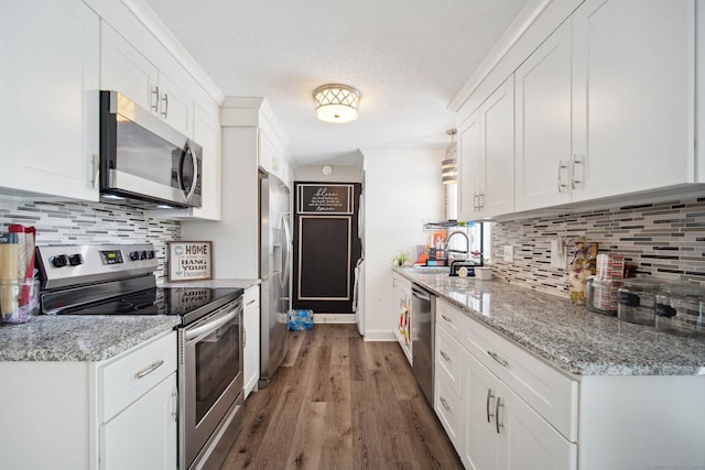 kitchen with white cabinets, appliances with stainless steel finishes, and light stone countertops