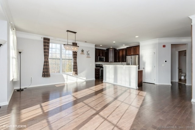 interior space featuring crown molding, hanging light fixtures, appliances with stainless steel finishes, a kitchen island, and dark brown cabinetry