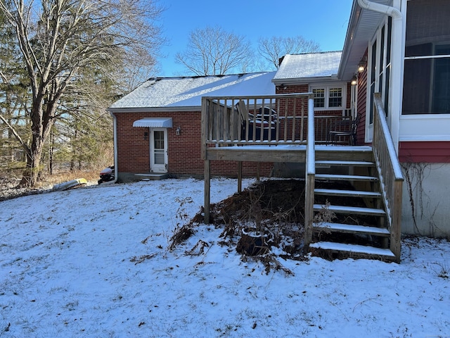 snow covered back of property with a wooden deck