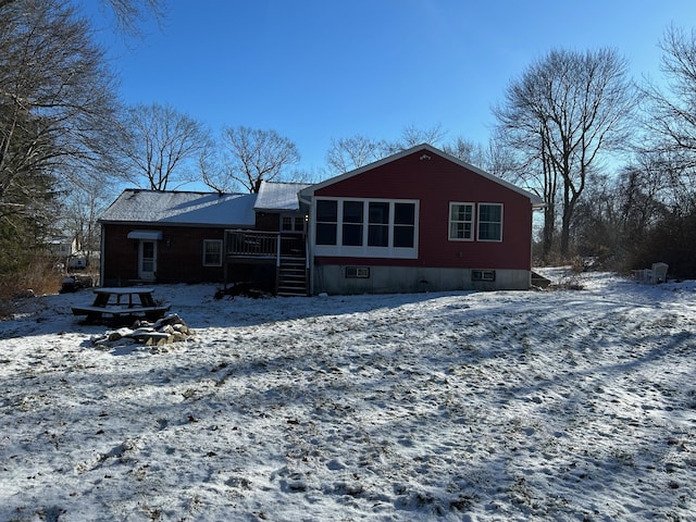 snow covered back of property featuring a wooden deck