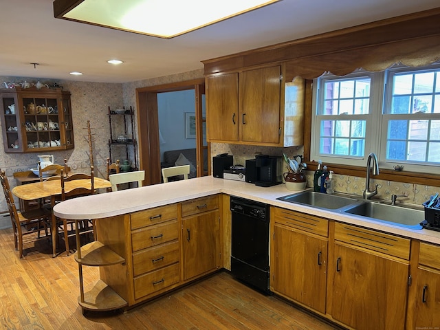 kitchen featuring sink, kitchen peninsula, black dishwasher, and light hardwood / wood-style flooring