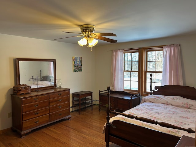 bedroom with baseboard heating, ceiling fan, and wood-type flooring