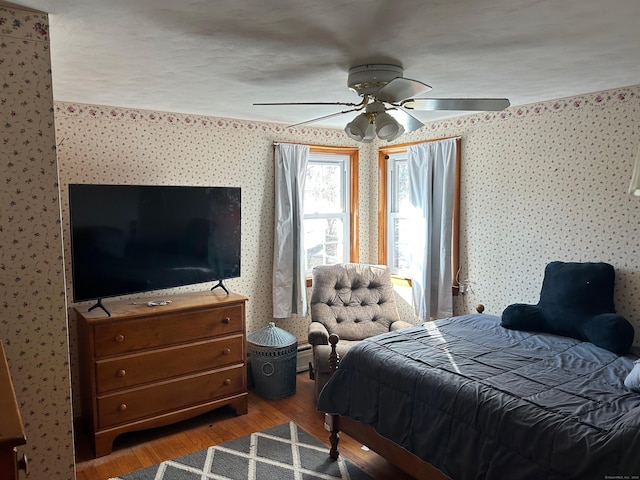 bedroom with hardwood / wood-style floors, ceiling fan, and baseboard heating