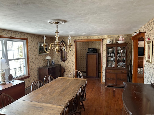 dining area featuring dark hardwood / wood-style floors, a baseboard heating unit, a textured ceiling, and an inviting chandelier