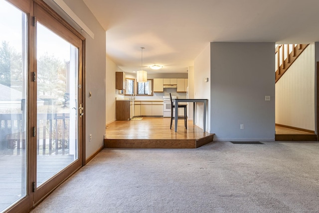 unfurnished living room featuring light colored carpet and sink