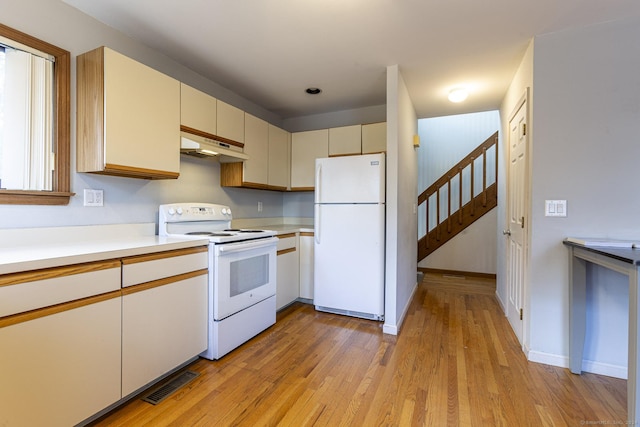 kitchen featuring cream cabinets, white appliances, and light hardwood / wood-style flooring