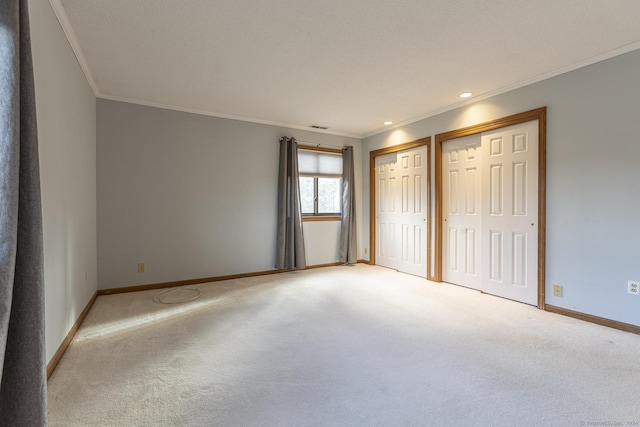 unfurnished bedroom featuring multiple closets, crown molding, and light colored carpet