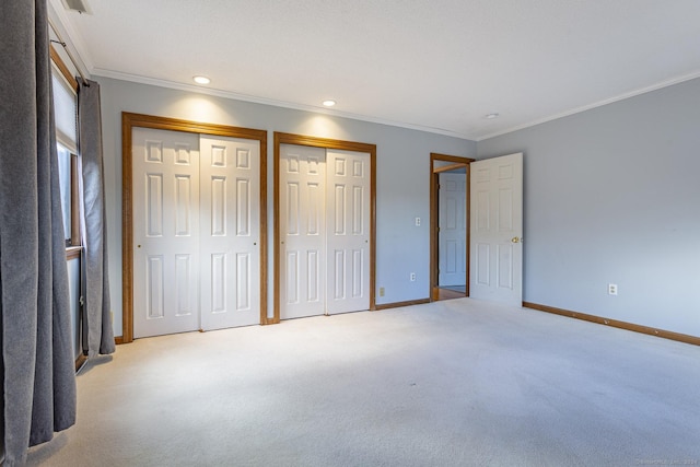 unfurnished bedroom with multiple closets, light carpet, and crown molding