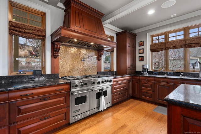 kitchen featuring decorative backsplash, dark stone counters, ornamental molding, sink, and double oven range