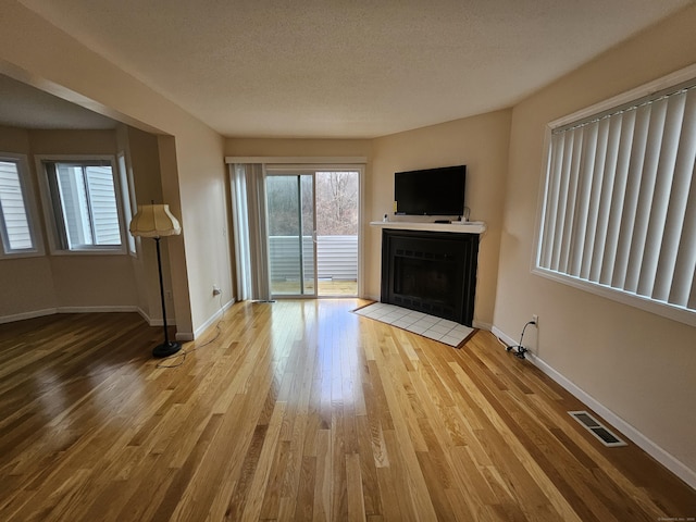 unfurnished living room with light hardwood / wood-style flooring and a textured ceiling