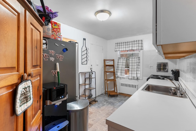 kitchen featuring radiator heating unit, sink, and stainless steel refrigerator