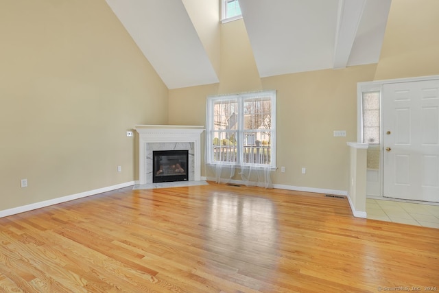 unfurnished living room with plenty of natural light, a high end fireplace, and light hardwood / wood-style floors