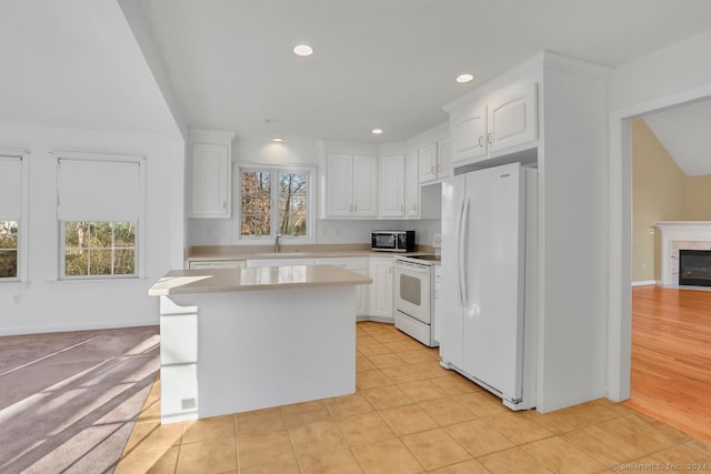 kitchen featuring white cabinetry, a center island, sink, light hardwood / wood-style flooring, and white appliances