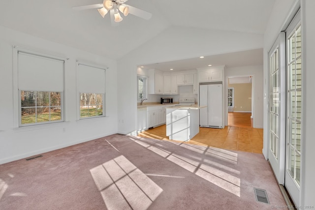 kitchen with white appliances, sink, light tile patterned floors, white cabinets, and lofted ceiling