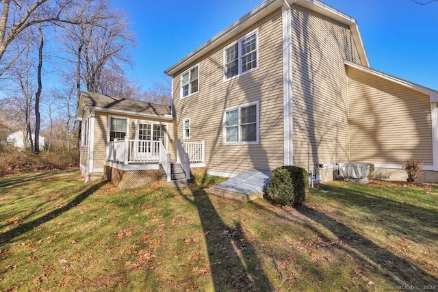 rear view of property featuring a lawn and a deck