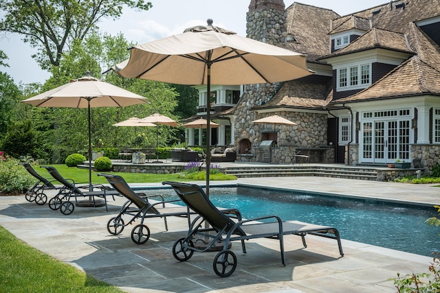 view of swimming pool with french doors, a patio area, and an outdoor stone fireplace