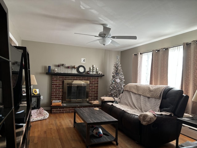 living room with hardwood / wood-style floors, ceiling fan, and a brick fireplace