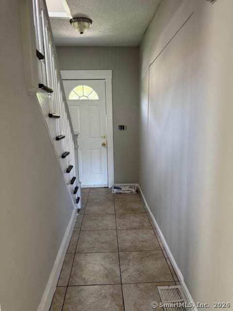 doorway to outside with tile patterned floors and a textured ceiling