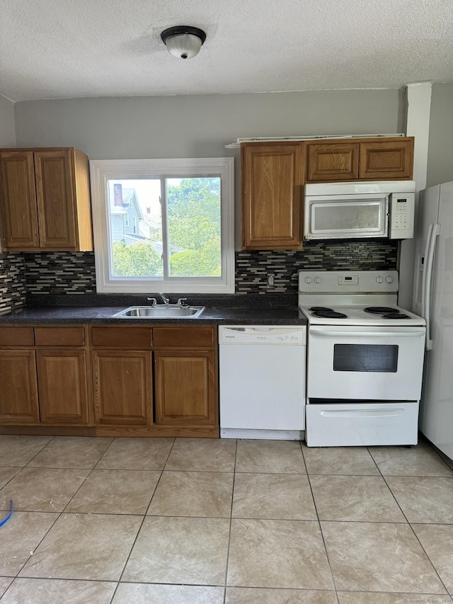 kitchen featuring a textured ceiling, sink, light tile patterned floors, and white appliances