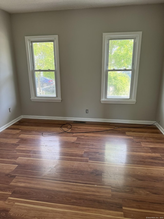 unfurnished room featuring dark hardwood / wood-style flooring and a wealth of natural light