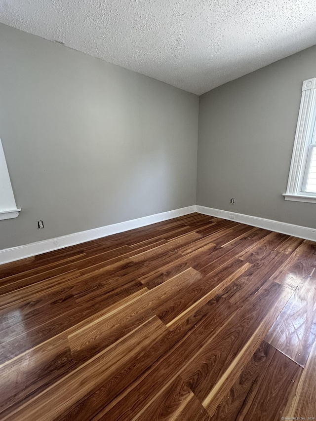 spare room featuring a textured ceiling and dark hardwood / wood-style floors