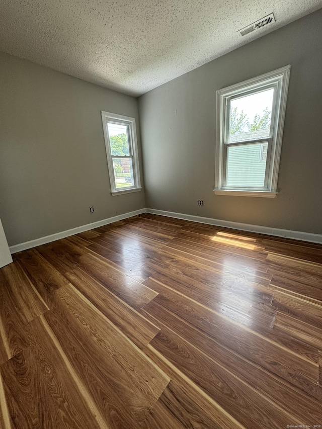 spare room with a textured ceiling and dark hardwood / wood-style flooring