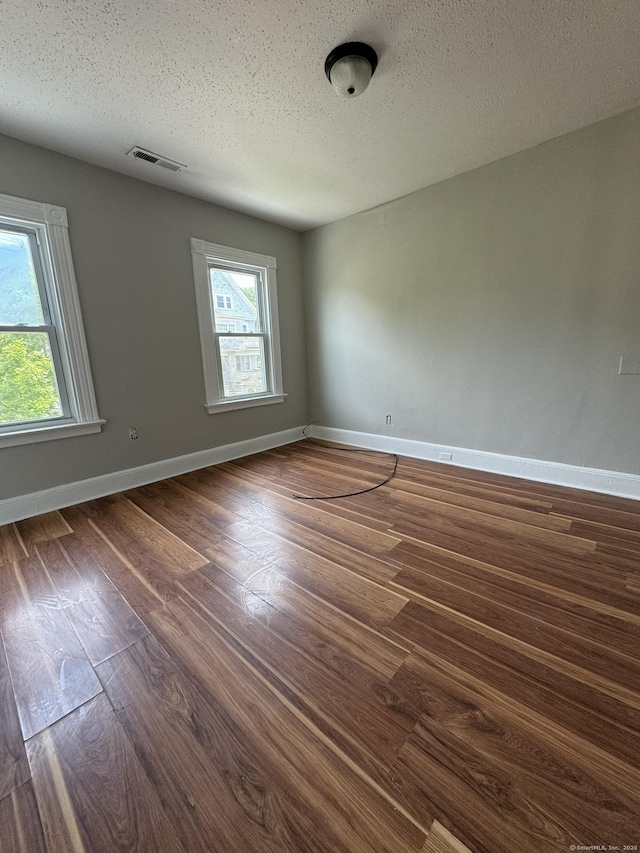 unfurnished room with a textured ceiling and dark wood-type flooring