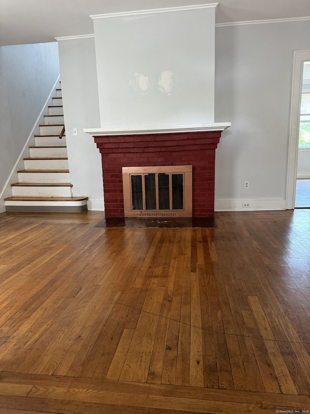 unfurnished living room with dark wood-type flooring, a brick fireplace, and crown molding