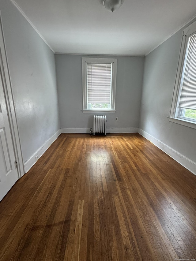 spare room featuring dark hardwood / wood-style flooring, plenty of natural light, radiator, and ornamental molding