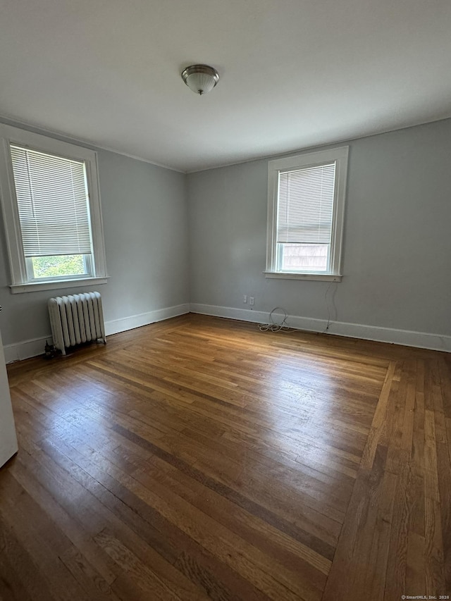 spare room with radiator heating unit and wood-type flooring